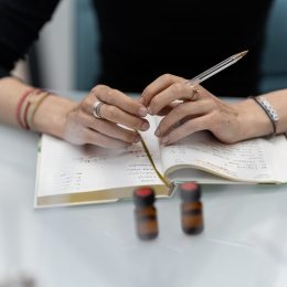 Mains posées sur un cahier de création chez Cinquième Sens, illustrant le processus de conception d'un parfum.