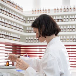 Femme en blouse de laboratoire chez Cinquième Sens, manipulant des ingrédients dans le processus de création de parfum